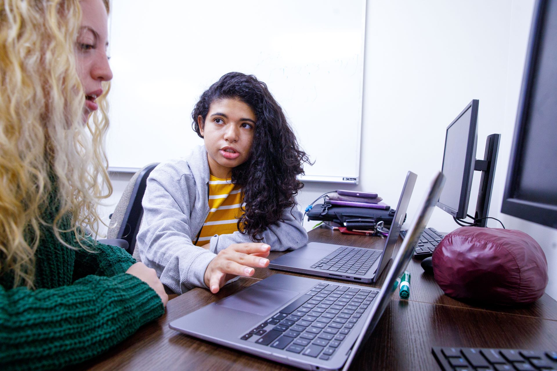 A student explaining to another student while they are sitting at a computer